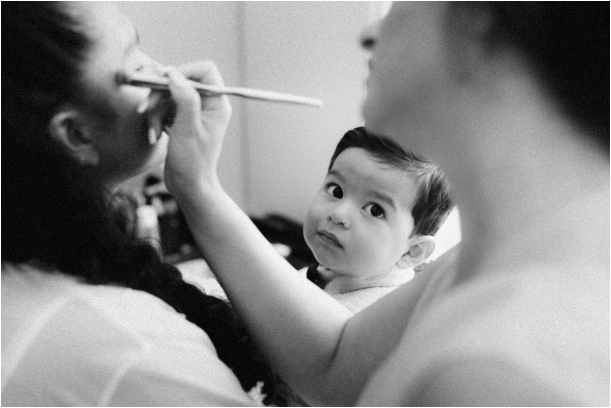 Foto in bianco e nero del trucco della sposa con il figlio in braccio che guarda verso l'obiettivo