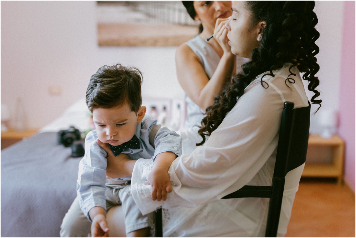 Andrea tiene in braccio il figlio mentre la truccatrice completa il make up della sposa