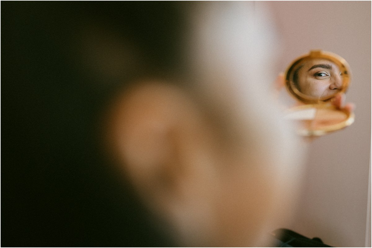 Lo sguardo della sposa riflesso in uno specchietto durante il trucco