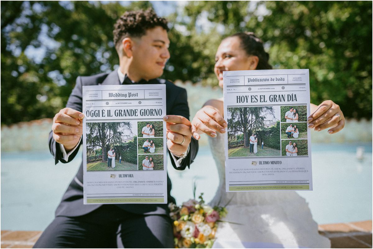 Andrea e Orlando mostrano due giornali personalizzati del matrimonio in italiano e spagnolo alla Tenuta La Ginestra in Sabina