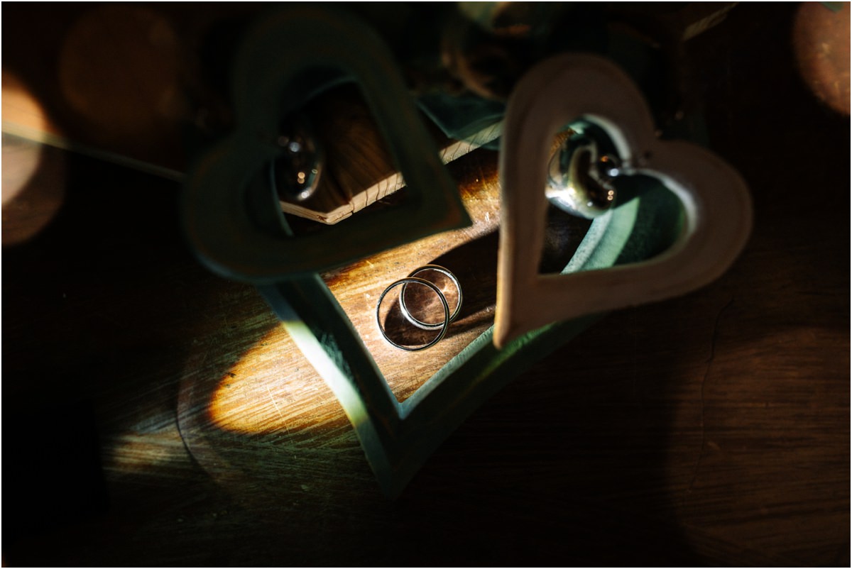 Le fedi di Andrea e Orlando tra due cuori di legno illuminati da una lama di luce