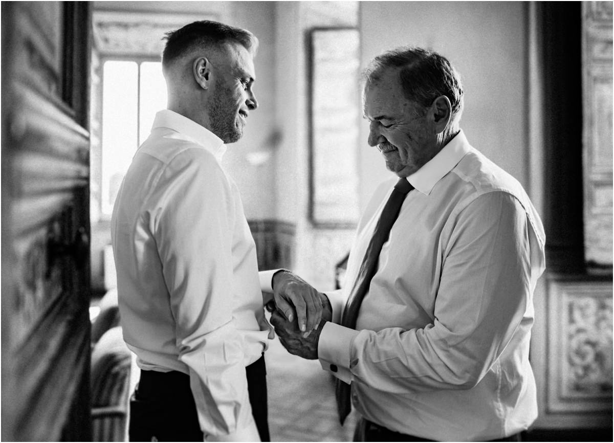 Groom Getting Ready with Family, Black and White Black and white photo of groom Angus smiling while a family member helps him with his shirt cuff