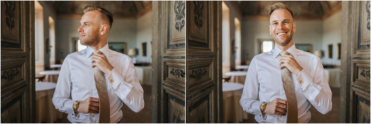 Groom Angus Ready by the Wooden Door Groom Angus smiling and adjusting his tie next to a carved wooden door at Villa Grazioli