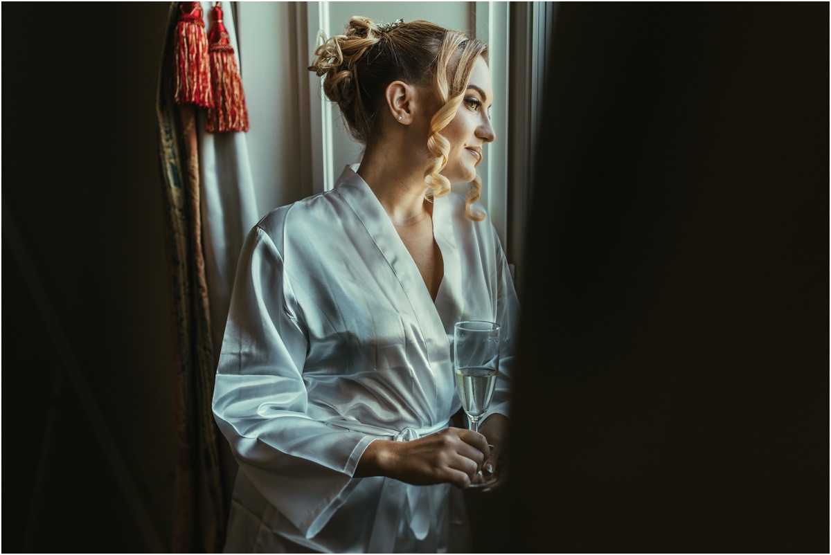 Bride Looking Out of the Window Bride Miriana holding a glass of champagne and gazing out of the window in soft light