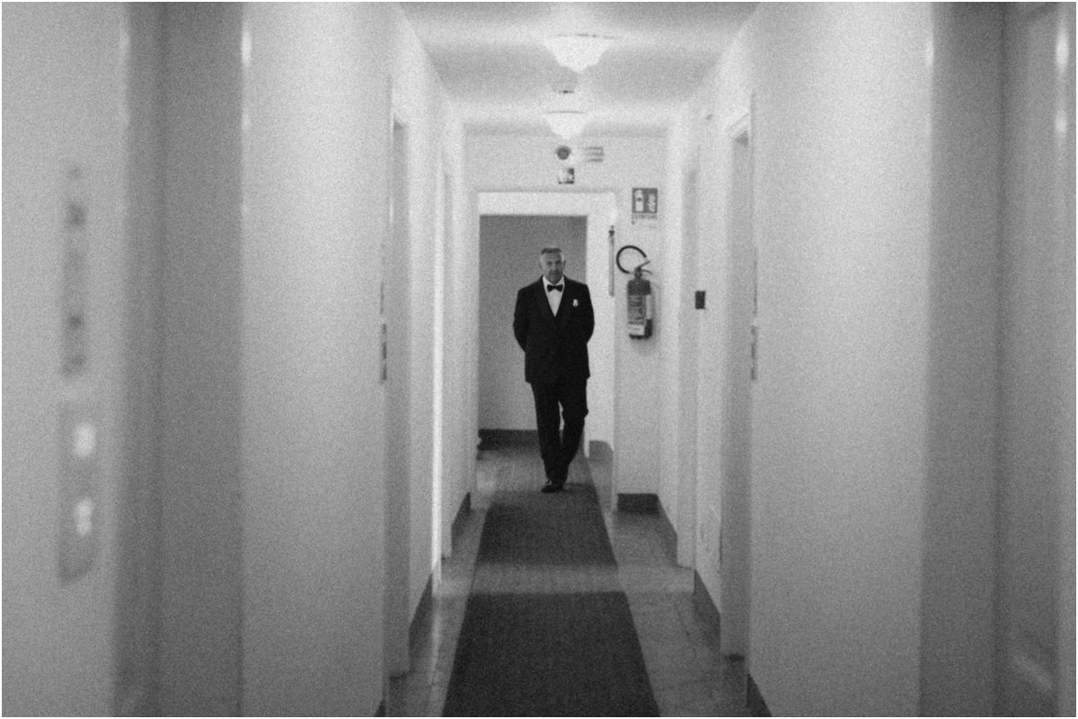 Coming Back Down the Corridor, Black and White Black and white photo of a man in a tuxedo walking towards the camera along a long corridor