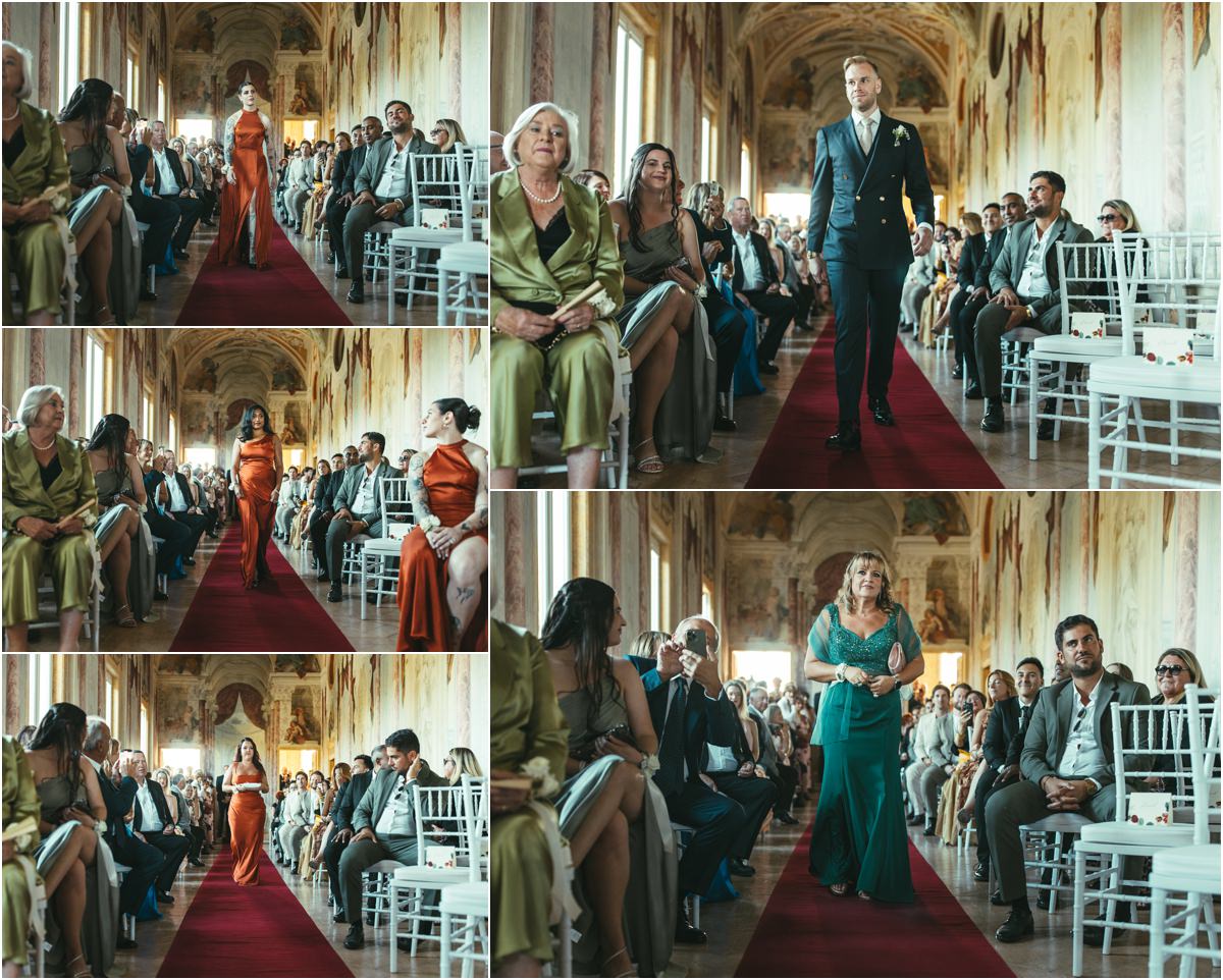 Bridesmaids Walking Down the Aisle in the Pannini Gallery Bridesmaids in orange dresses, a woman in green and groom Angus walking down the red aisle of the Pannini Gallery at Villa Grazioli