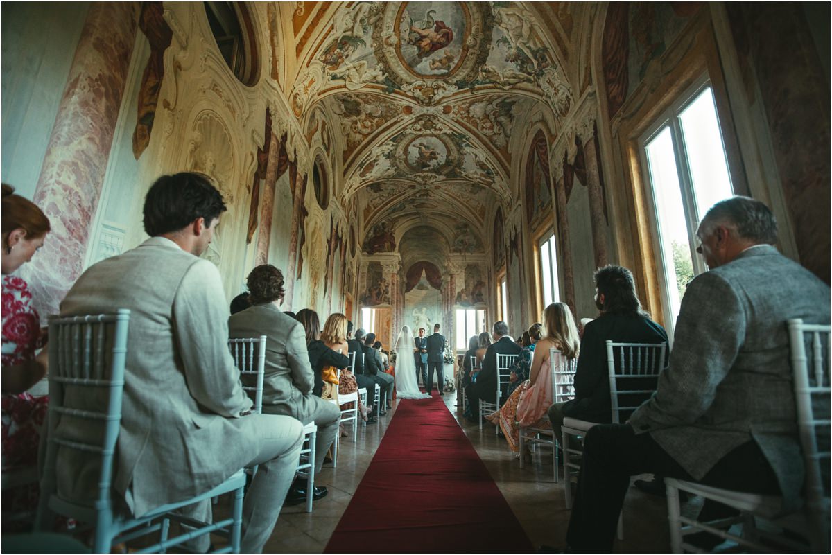 Guests Seated in the Pannini Gallery Guests seated along the red aisle of the Pannini Gallery during the civil ceremony at Villa Grazioli