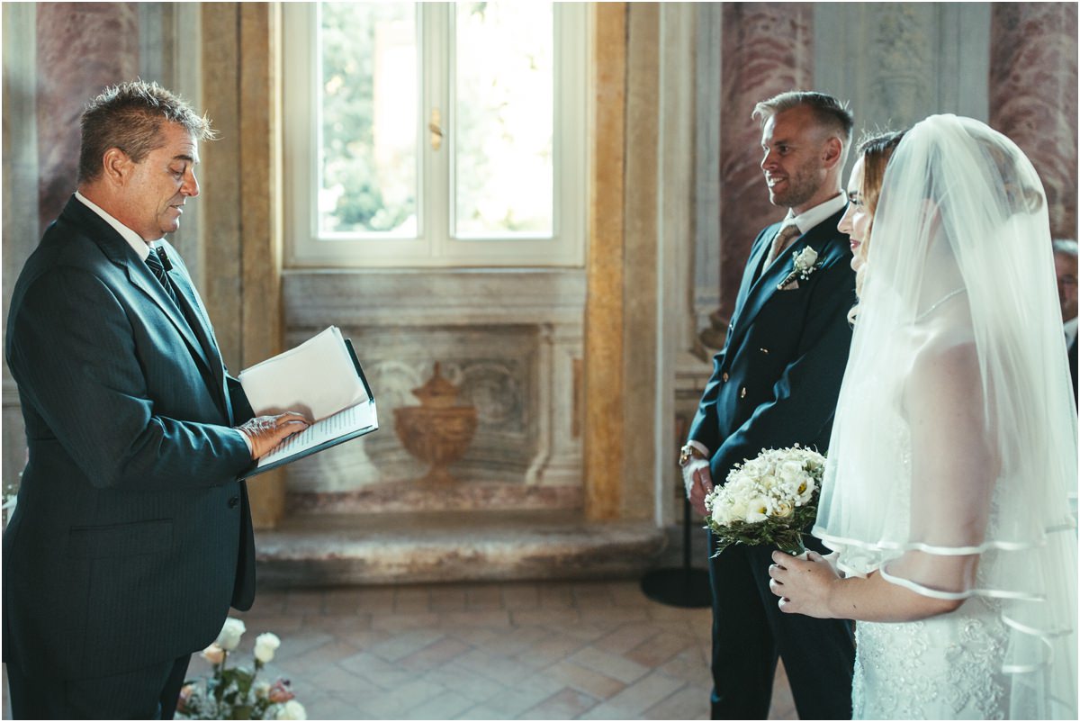 Officiant Reading During the Civil Ceremony Officiant reading the civil ceremony while Miriana and Angus listen in the Pannini Gallery at Villa Grazioli