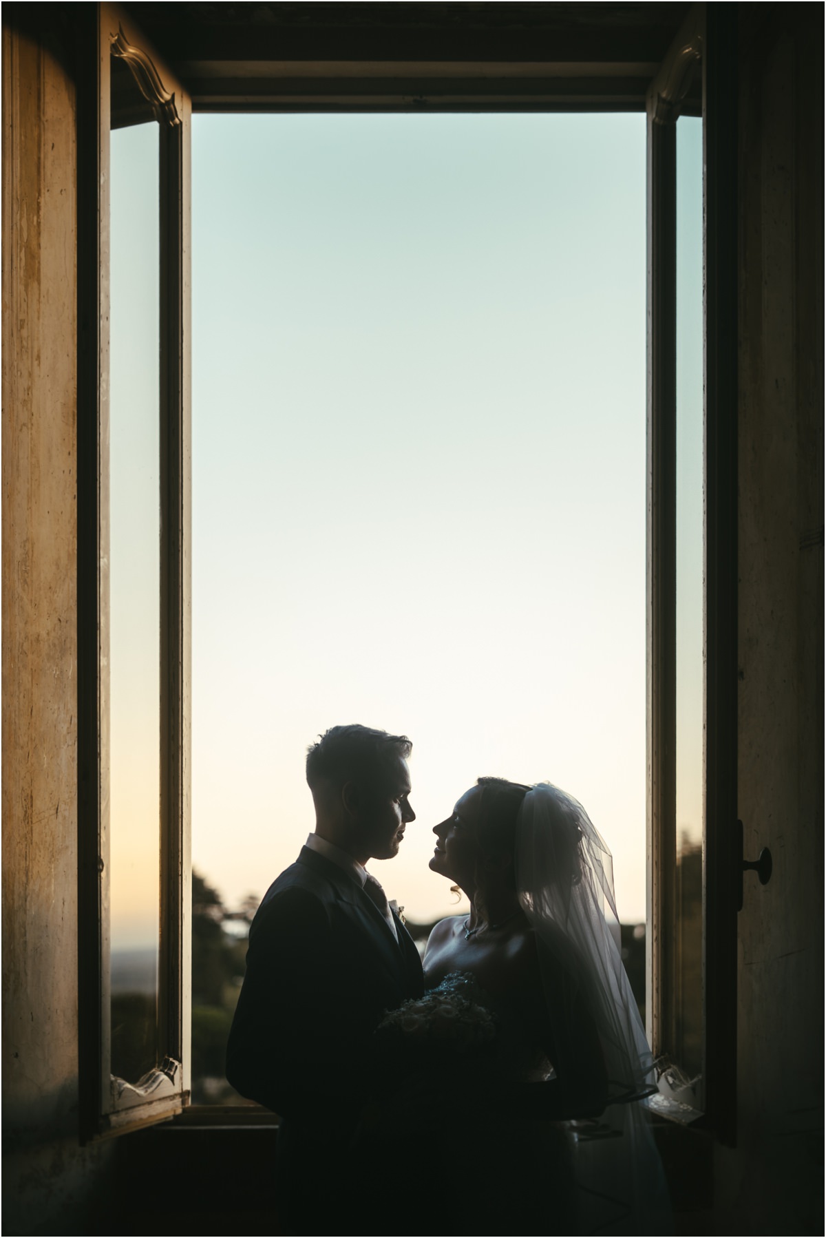 Couple Silhouette in a Window at Dusk Silhouette of Miriana and Angus facing each other in an open window of Villa Grazioli at dusk