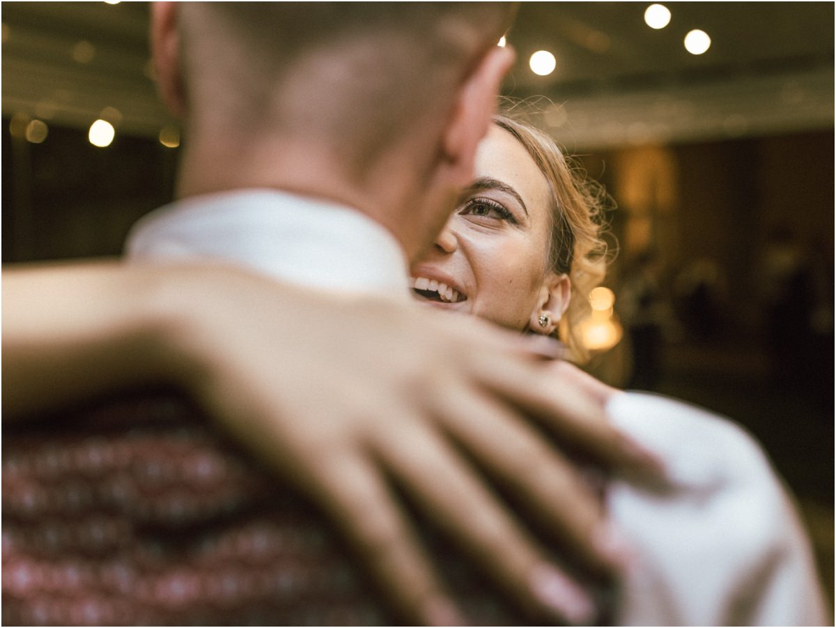 Bride Smiling in the Groom's Arms Miriana smiling over the shoulder of Angus as they dance close under warm lights