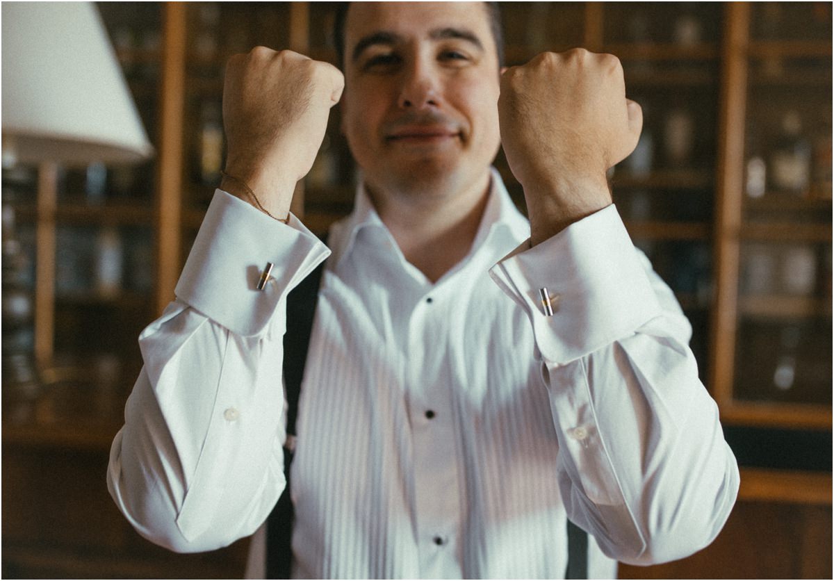 Cufflinks On Groom Alessio raising his fists to show his cufflinks in the library room of Villa Grazioli