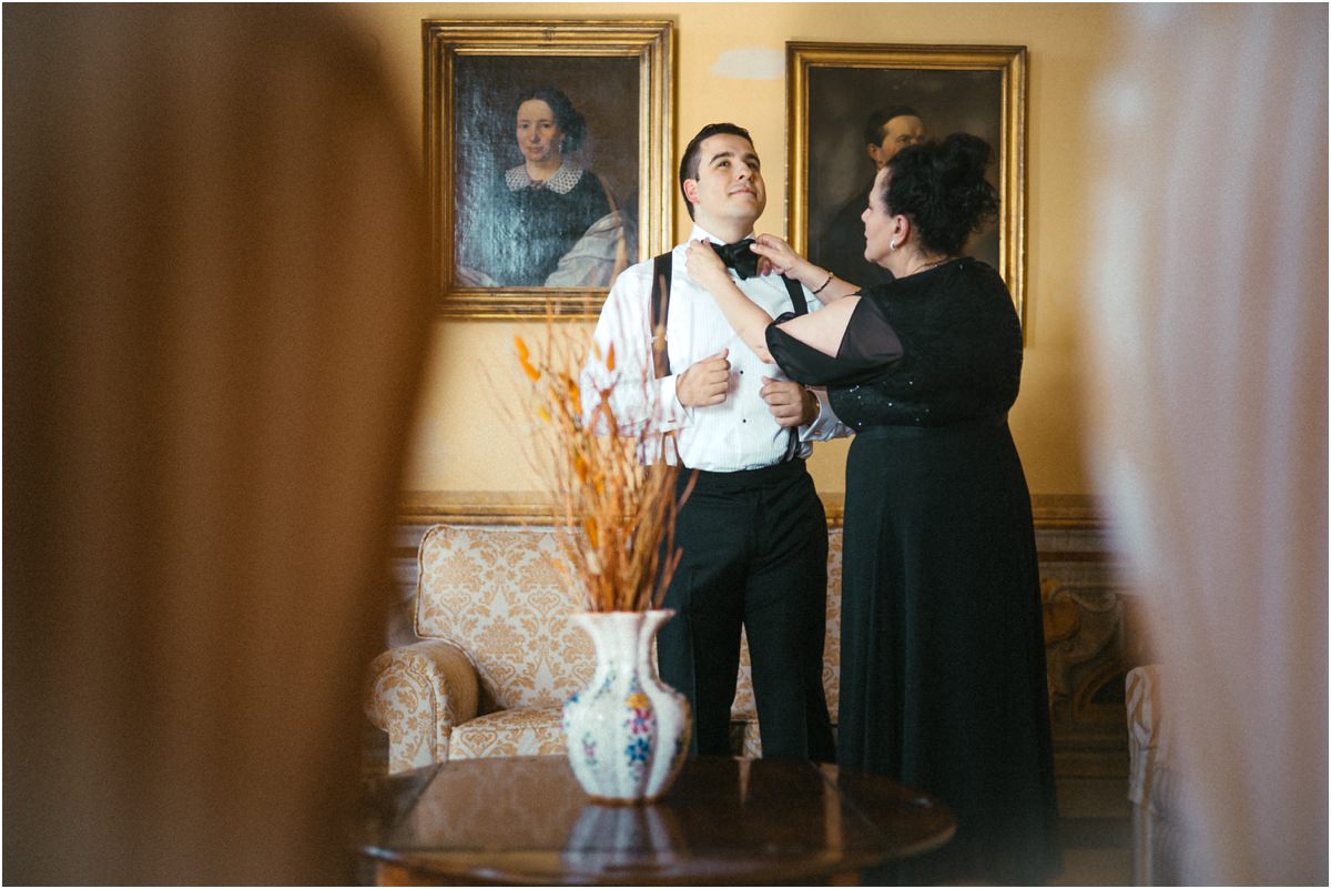 Last Adjustments to the Bow Tie Groom Alessio having his bow tie adjusted by a family member, seen through a doorway at Villa Grazioli