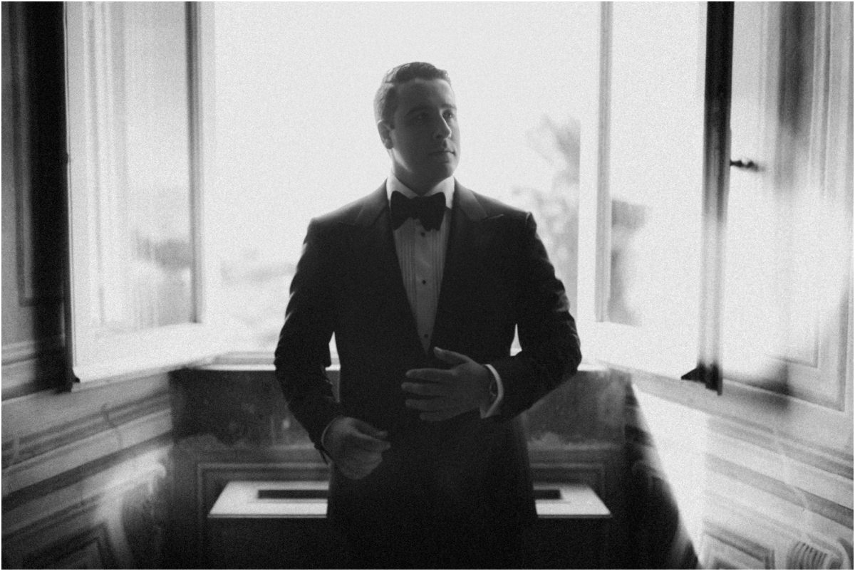 Groom Silhouette, Black and White Black and white silhouette of groom Alessio buttoning his jacket against a bright window
