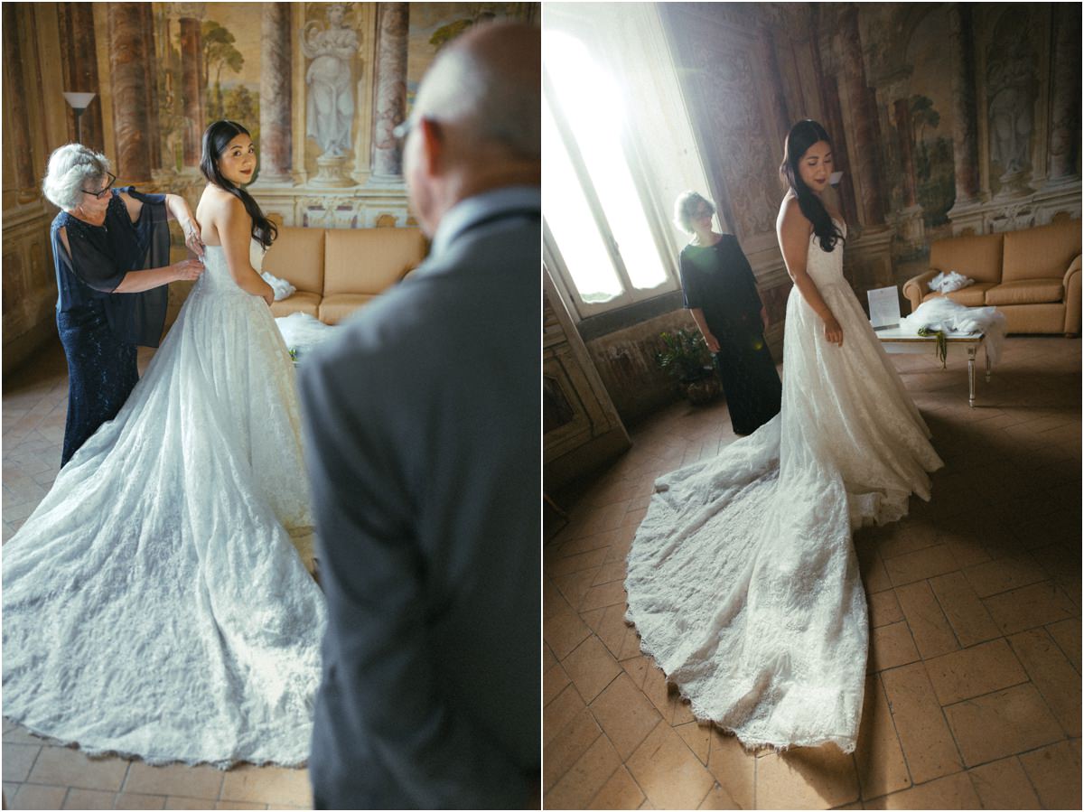 The Long Train Bride Leah with her long lace train spread on the floor while family members help her get dressed
