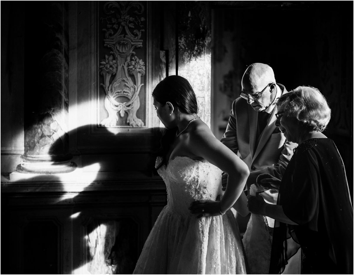 Fastening the Dress, Black and White Black and white photo of two family members fastening bride Leah's dress, with strong shadows on the wall