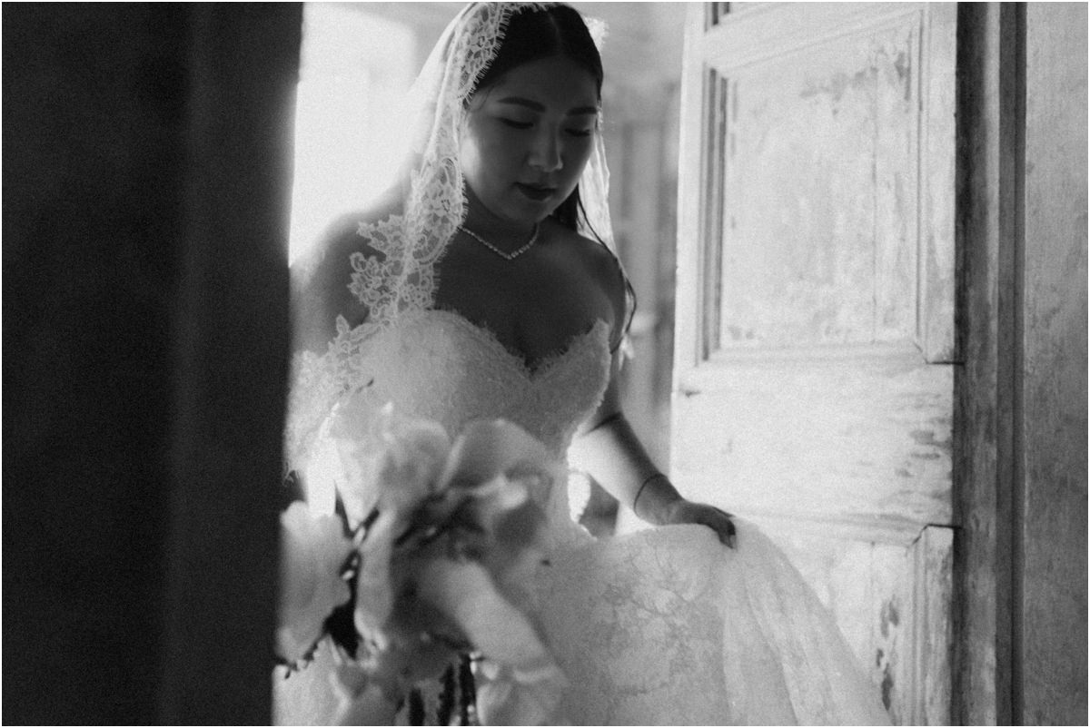 Bride by the Old Door Black and white close portrait of bride Leah with lace veil and white orchids by an old wooden door