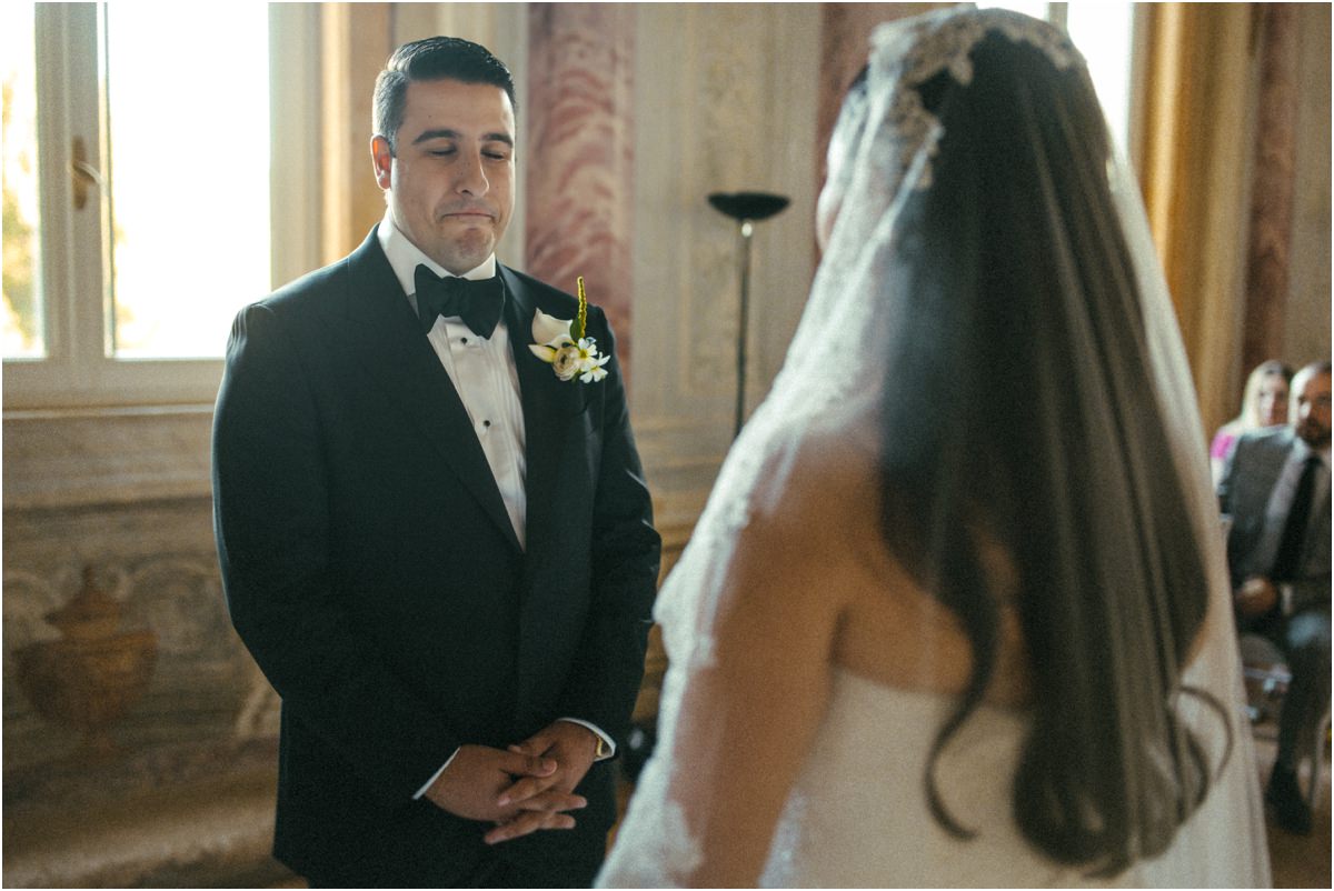 Alessio Looking at Leah Groom Alessio with his hands clasped, looking at bride Leah during the civil ceremony at Villa Grazioli