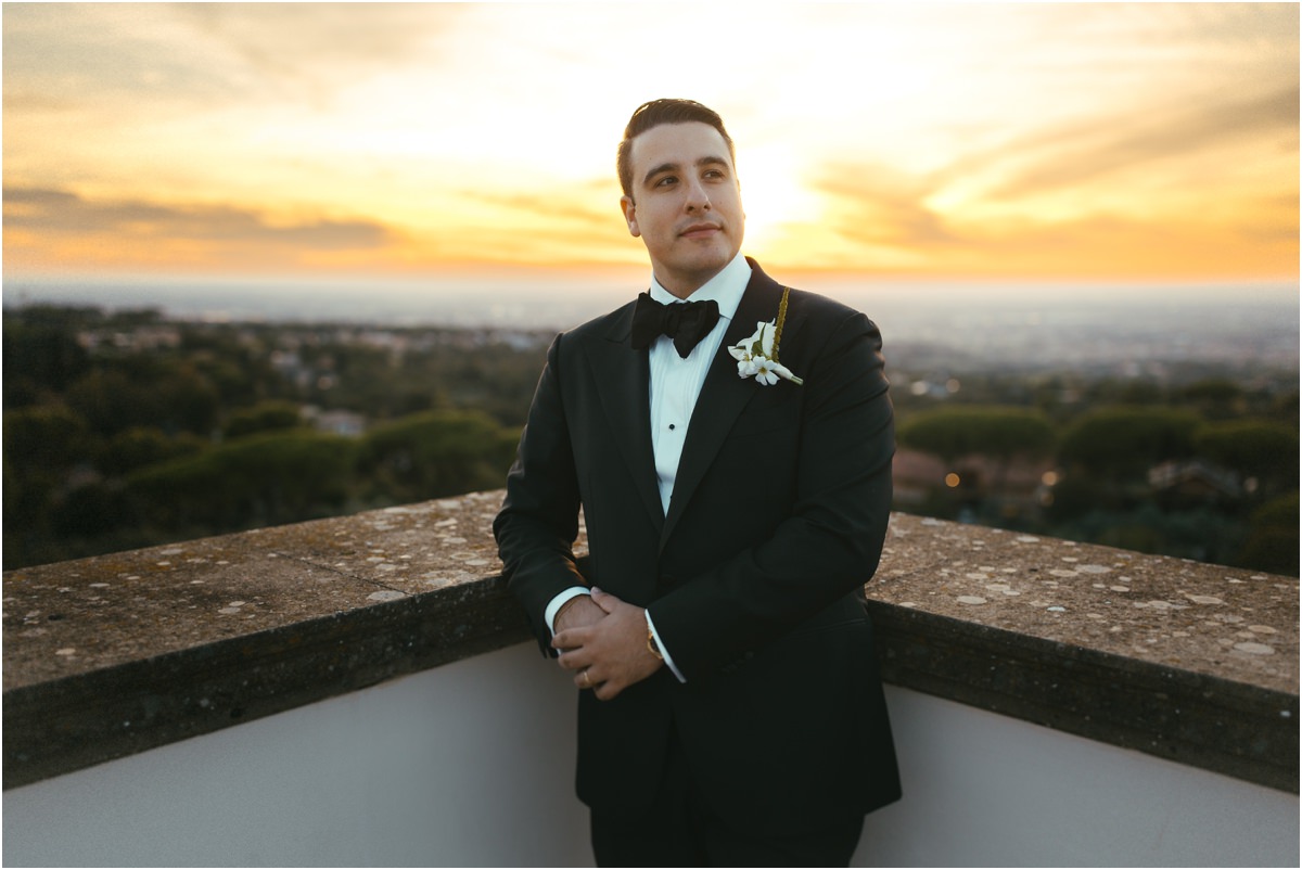 Groom Portrait at Sunset Groom Alessio leaning on the terrace wall of Villa Grazioli with the sunset behind him