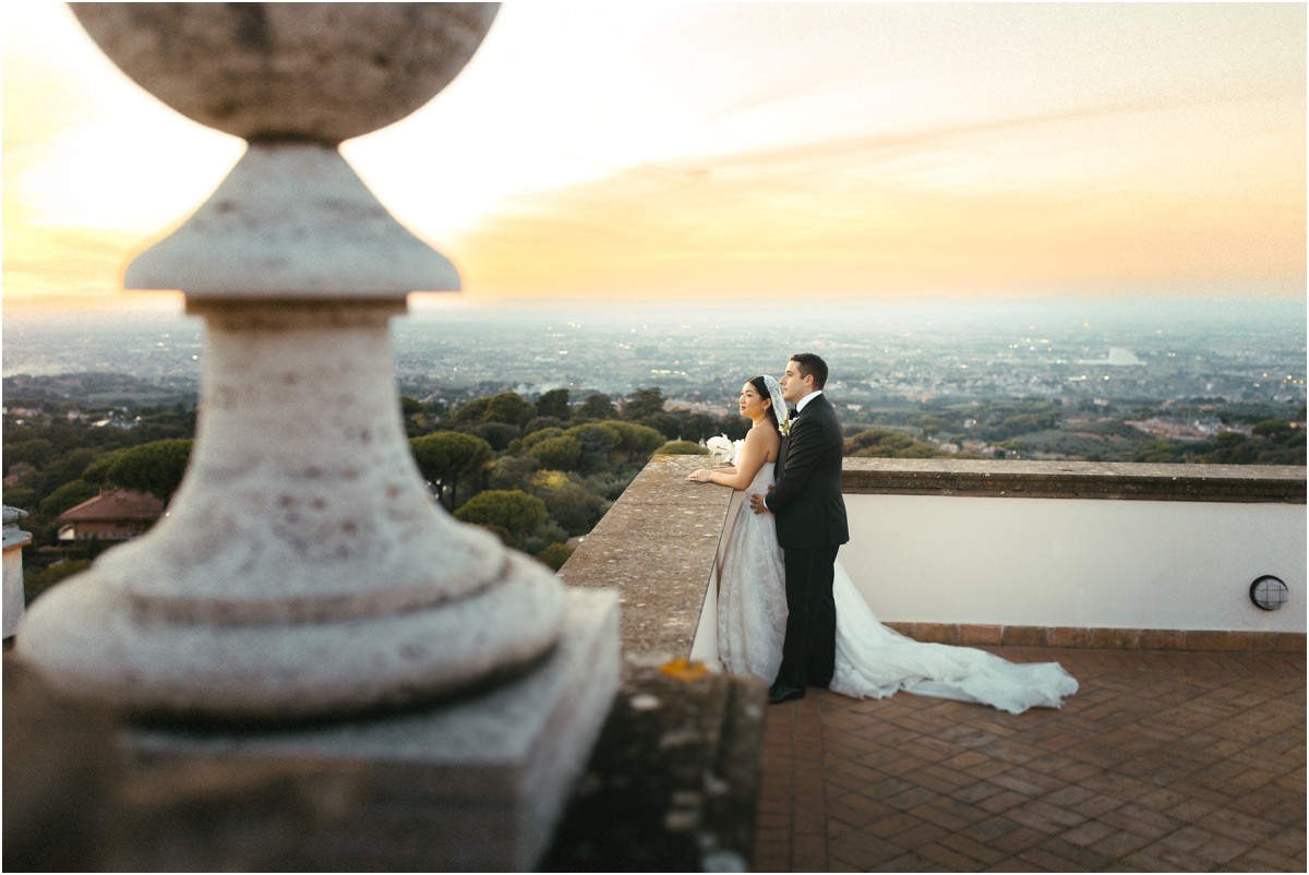 Couple on the Terrace of Villa Grazioli Alessio and Leah on the terrace of Villa Grazioli behind a stone finial, the plain below at sunset