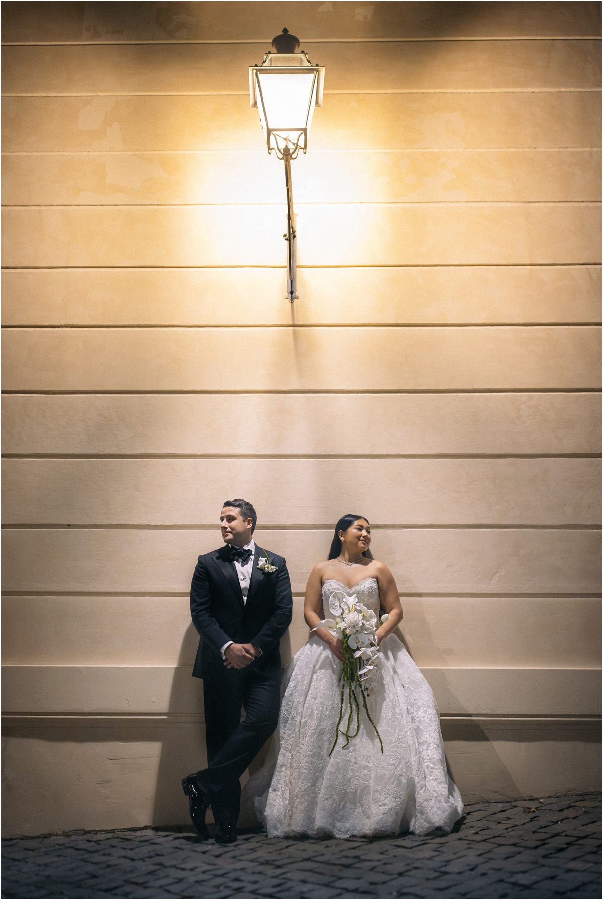 Under the Lantern Alessio and Leah leaning against the wall of Villa Grazioli under a lit lantern at dusk