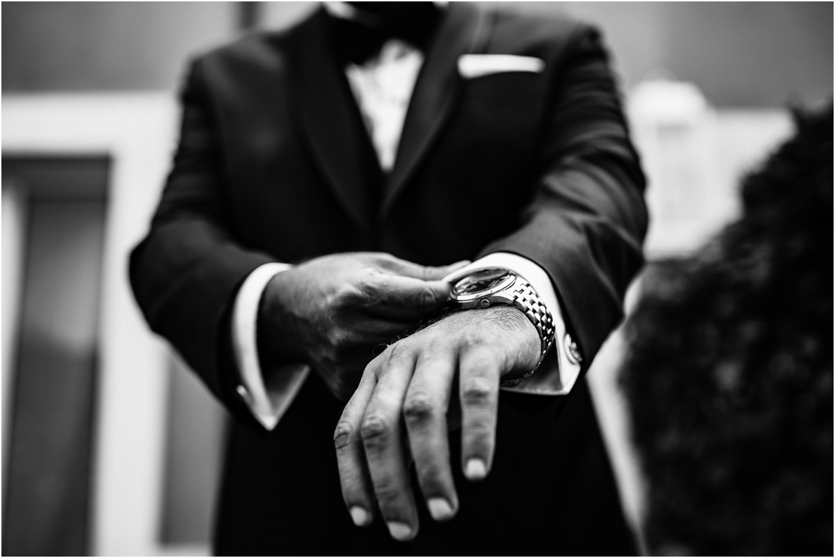Le mani di Davide Mani dello sposo con l'orologio sul polsino dello smoking, dettaglio in bianco e nero