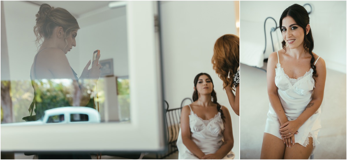 Allo specchio Martina seduta durante il trucco, riflessa nello specchio insieme a un'amica che si scatta una foto