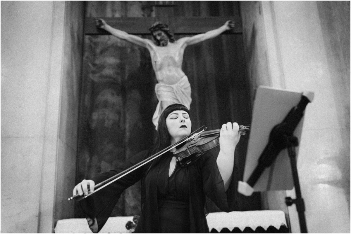 Il violino Violinista suona durante la messa sotto il crocifisso della basilica, foto in bianco e nero