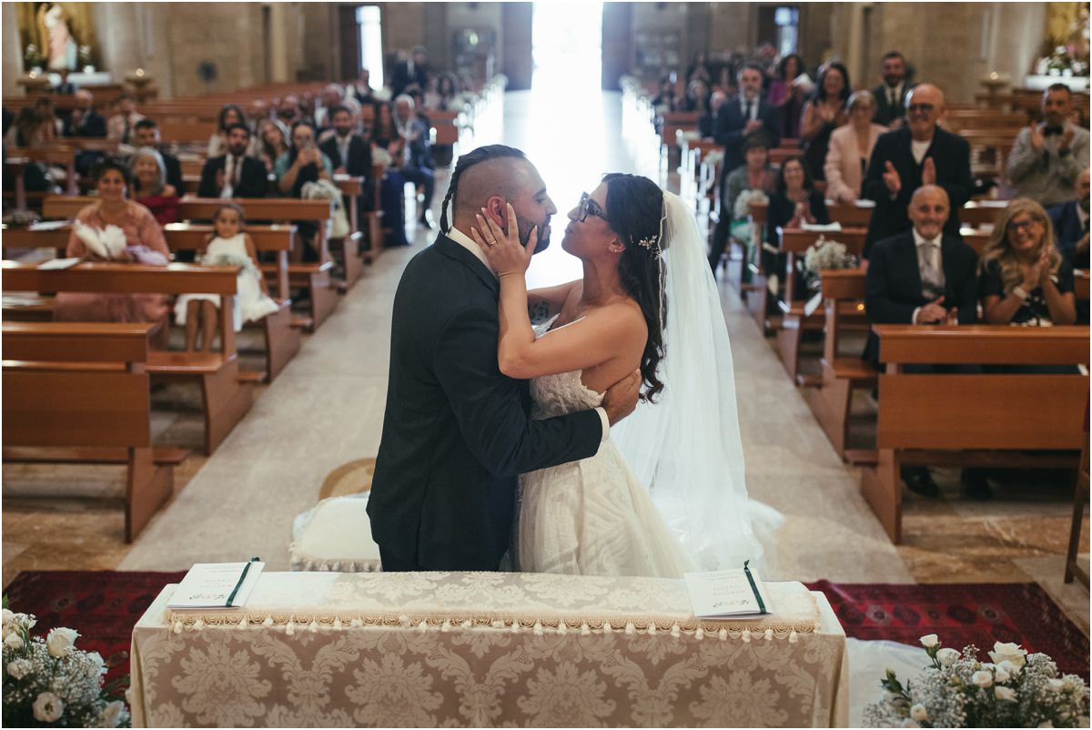 Il bacio Martina e Davide si baciano all'altare mentre gli ospiti applaudono dai banchi