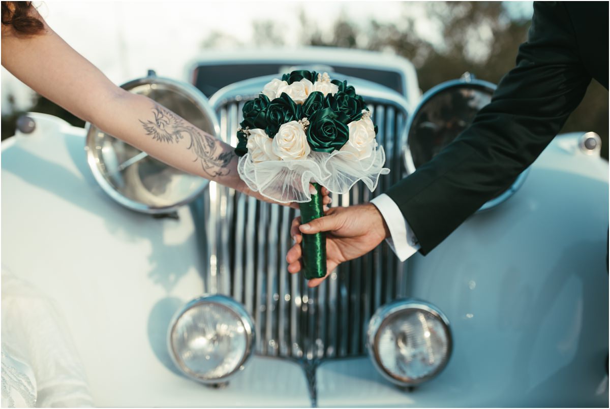 Il bouquet Mani di Martina e Davide che reggono il bouquet di rose verdi e bianche davanti alla calandra dell'auto d'epoca
