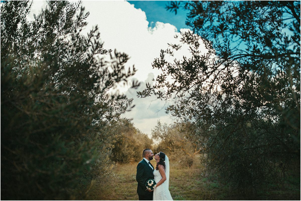 Tra gli ulivi Martina e Davide abbracciati in fondo a un sentiero tra gli ulivi di Le Jardin Potager