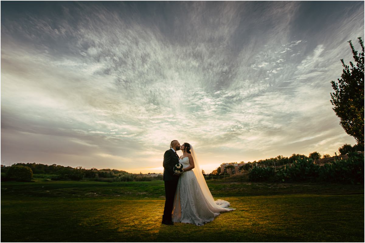 Il tramonto Martina e Davide si baciano nel prato di Le Jardin Potager al tramonto, sotto un cielo di nuvole