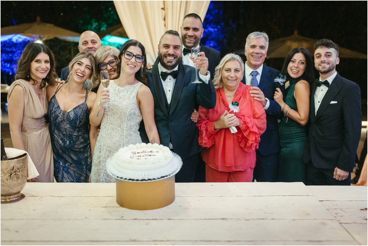 Brindisi con la torta Martina e Davide brindano con famiglia e amici dietro una torta decorata con la panna