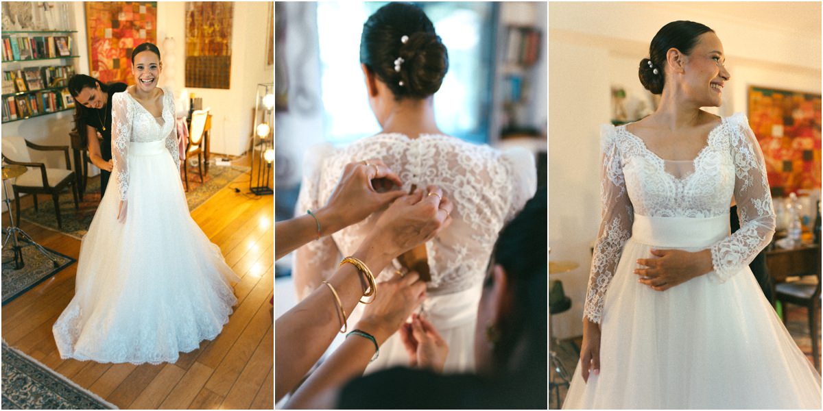 Abito da sposa in pizzo, bottoni Alice con l'abito da sposa in pizzo mentre le chiudono i bottoni sulla schiena