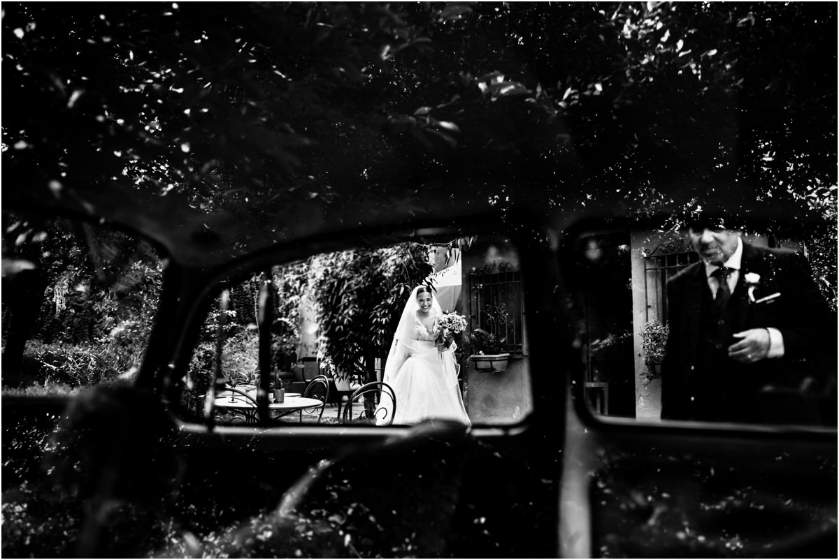 Sposa e papà verso l'auto Alice e il papà vicino all'auto degli sposi, visti dal finestrino, in bianco e nero