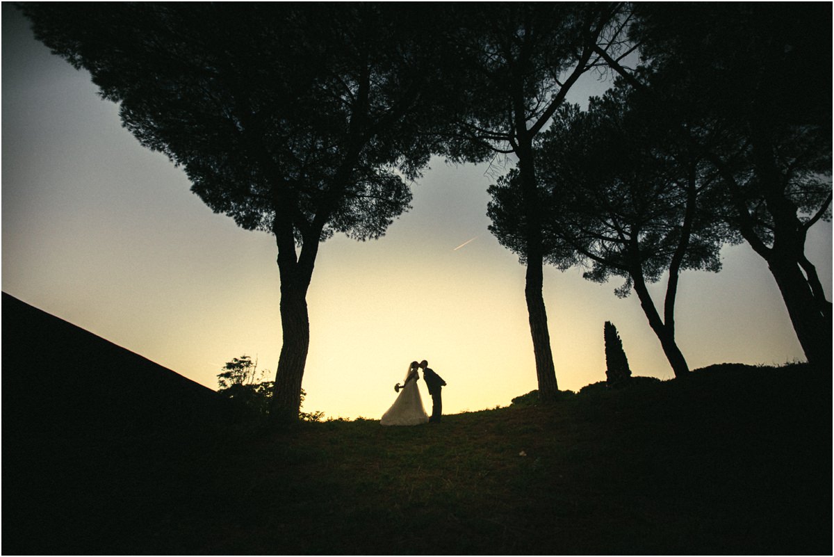 Silhouette degli sposi al tramonto Silhouette del bacio di Alice e Valerio tra i pini al tramonto