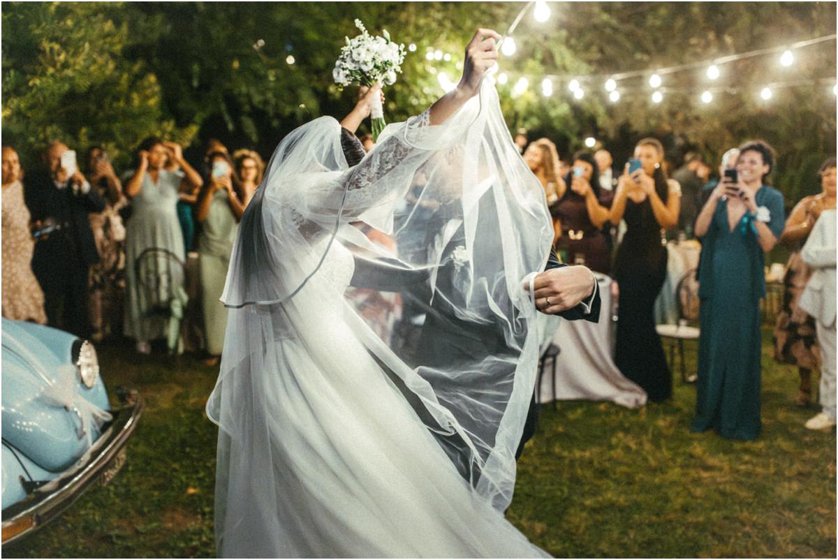 La sposa balla con il bouquet Alice balla con il bouquet alzato e il velo al vento tra gli invitati